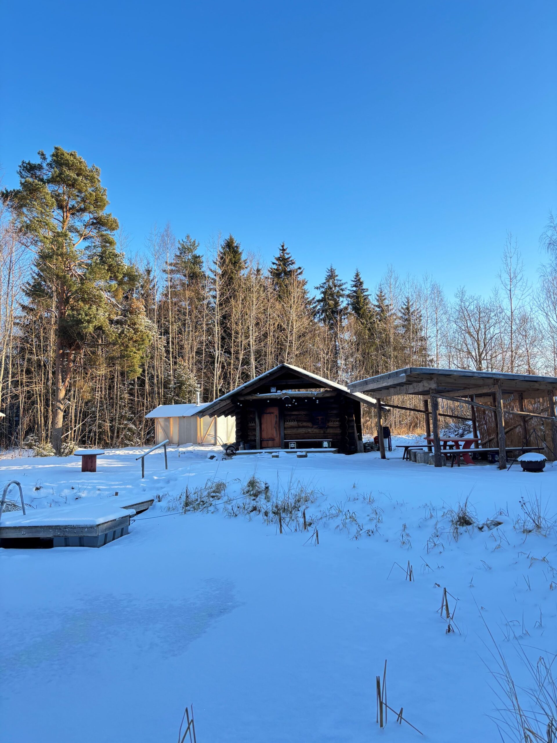 Smokesauna in Jantsu Farm-winter Winter view of a traditional smoke sauna and a frozen pond in a snowy landscape